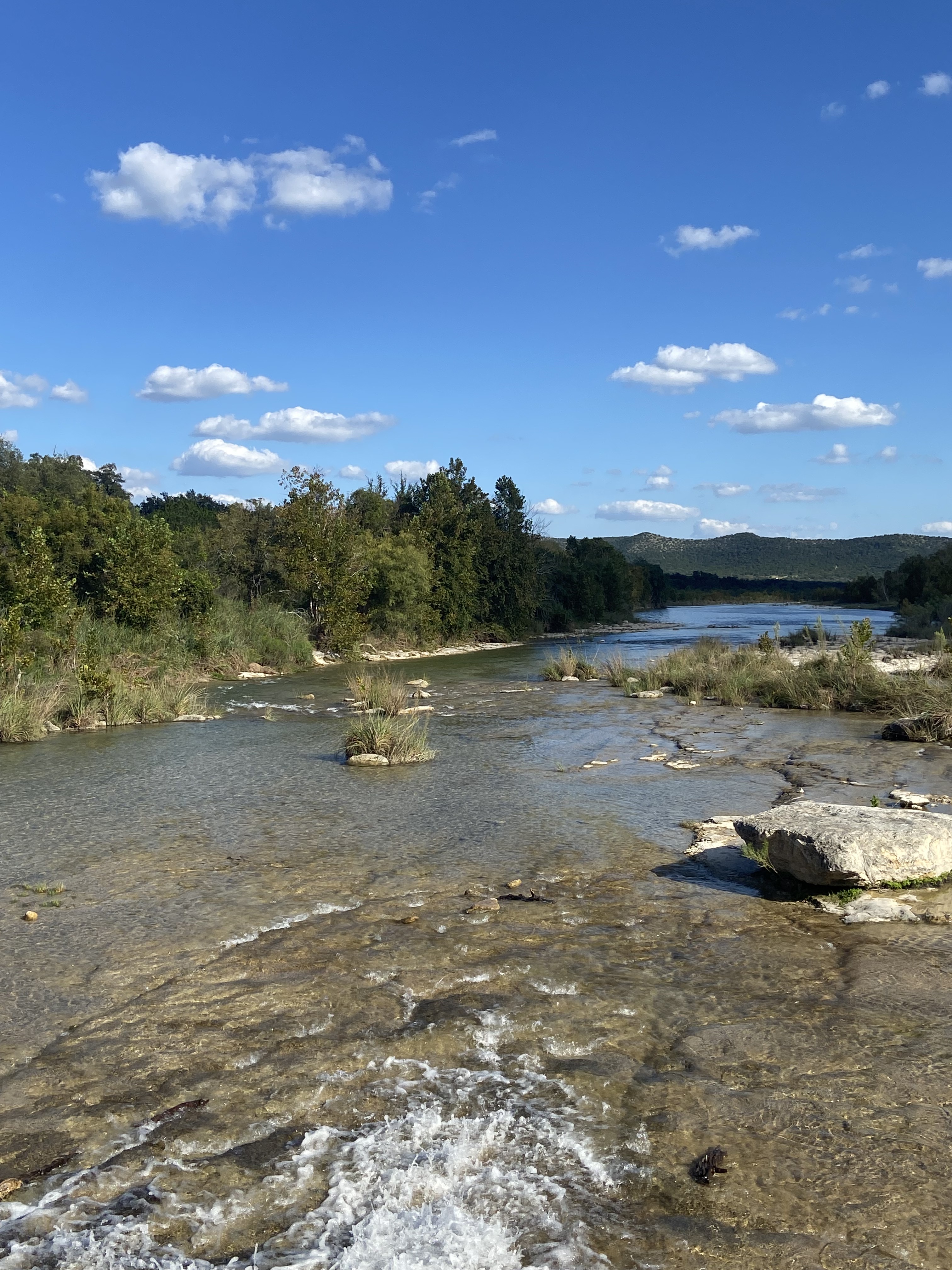 Clear shallow river flowing through Texas Hill Country limestone and trees.